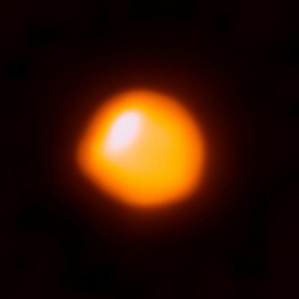 Bright red-orange blob with white spot and a bump on it, on black background.